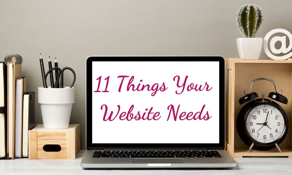 Laptop sitting on desk with words 11 Things your website needs on it in pink